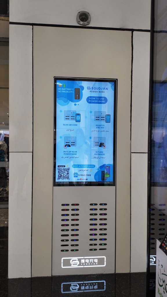 Wall-embedded SouDian power-bank dispenser in a Dubai retail corridor